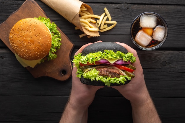 Frische leckere Burger mit Pommes Frites, Getränk auf der Holztischplatte.