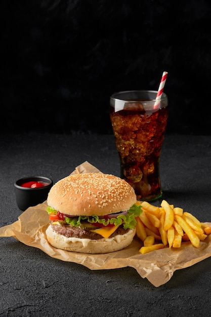 Frische leckere Burger Pommes Frites und Erfrischungsgetränk auf dunklem Hintergrund