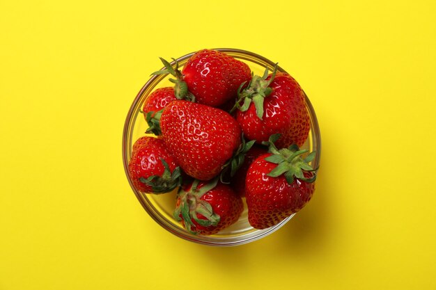 Frische leckere Erdbeere auf gelber Oberfläche, Ansicht von oben