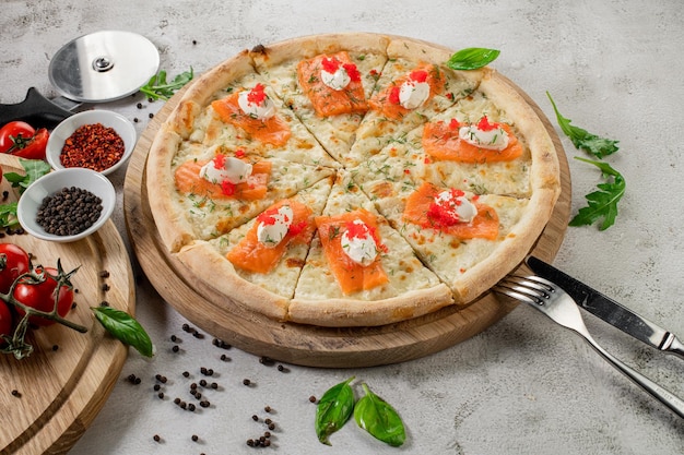 Frische leckere Pizza mit Lachs und Käse auf dem konkreten Hintergrund