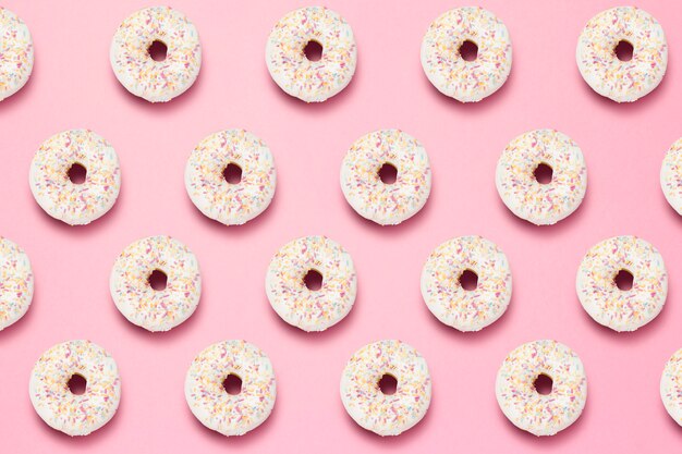 Frische leckere süße Donuts auf einem rosa Hintergrund. Muster.