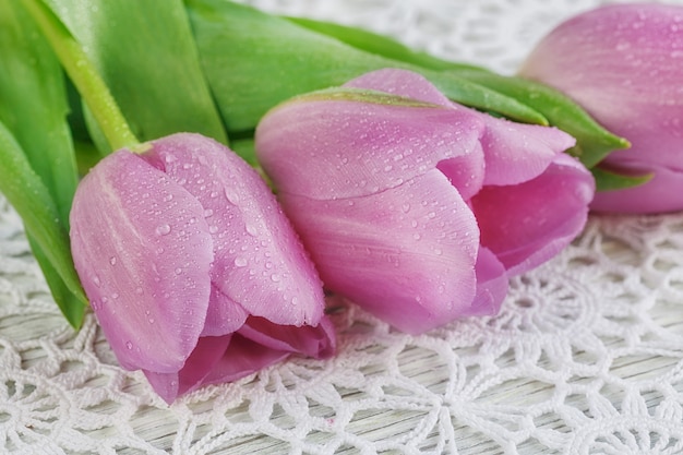 Frische lila Tulpen auf einer schönen gehäkelten Tischdecke