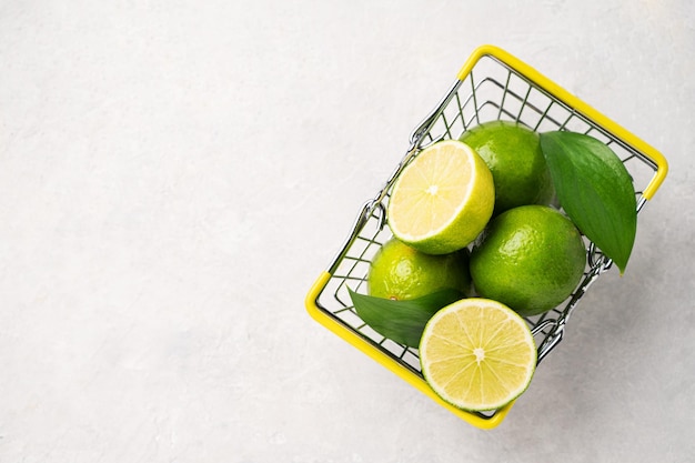 Frische Limetten in einem Supermarktkorb auf leicht strukturiertem Hintergrund Zitrusfruchtkonzept für frisch gepressten Limettenmojito Kopierbereich und Draufsicht