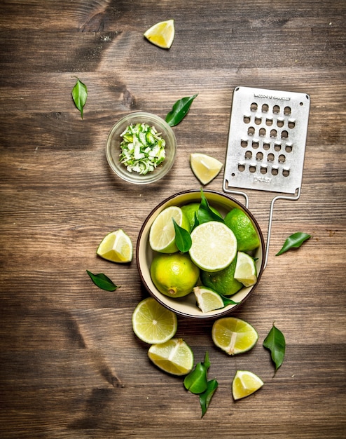 Frische Limetten mit Reibe und Schale auf einem Holztisch