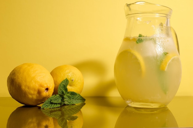 Frische Limonade auf einem gelben Hintergrund mit Zitronen und Minze