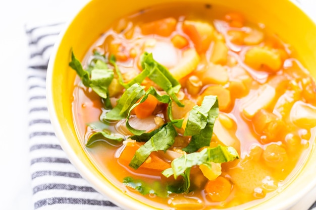 Frische Linsensuppe, garniert mit frischem Spinat in einer Schüssel.