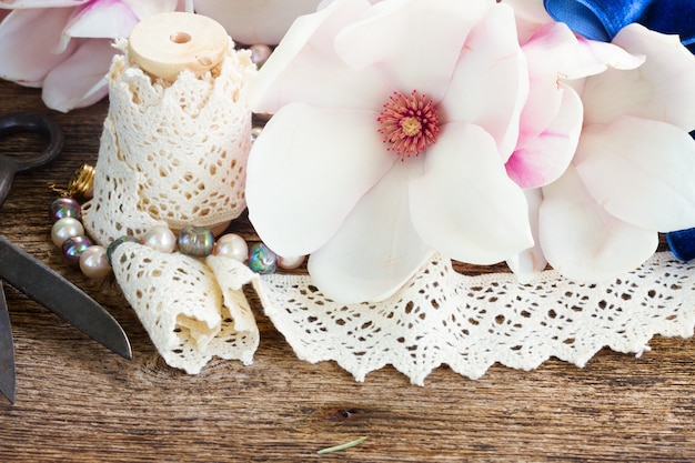 Frische Magnolienblumen mit Perlen und Vintage-Spitze auf Holztisch