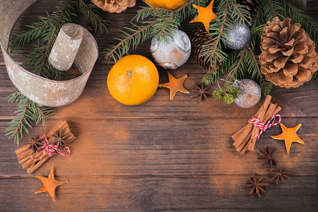 Frische Mandarinen mit Gewürzen und Weihnachtsdekoration mit Weihnachtsbaum auf dunklem altem Holztisch. Rustikaler Stil. Winterferienkonzept. Draufsicht mit Platz für Text