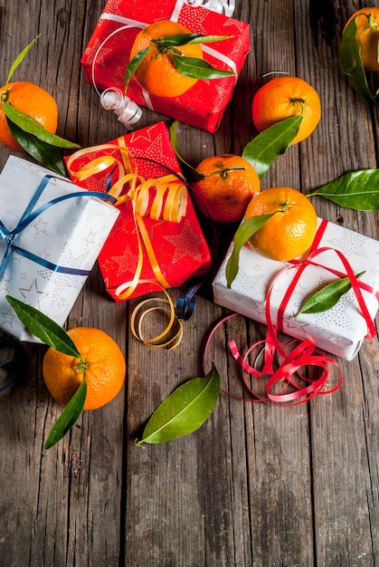 Frische Mandarinen mit grünen Blättern in einem weißen Korb, in einer Weihnachtsdekoration und in Geschenkboxen