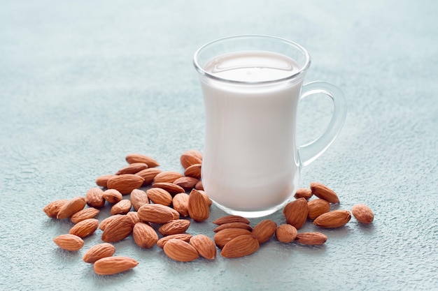 Frische Mandelmilch in einem Glas und Nüsse daneben auf einem Leuchttisch. Alternative Ernährung, Vitaminquelle