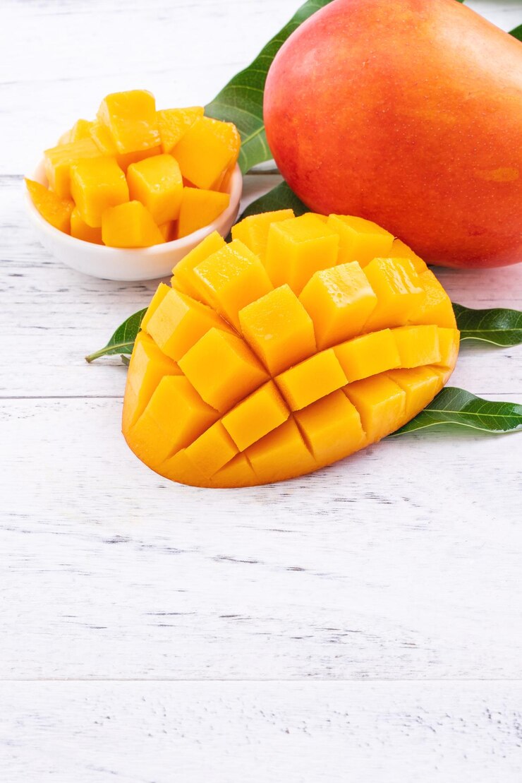 Frische Mango, schöne gehackte Früchte mit grünen Blättern auf hellem Holztischhintergrund. Designkonzept für tropische Früchte, Nahaufnahme, Kopienraum.