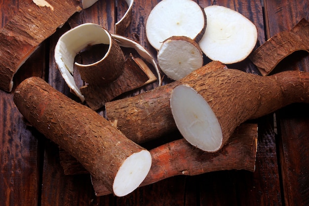 Frische Manioka und Schalen und Scheiben auf rustikalem Holztisch