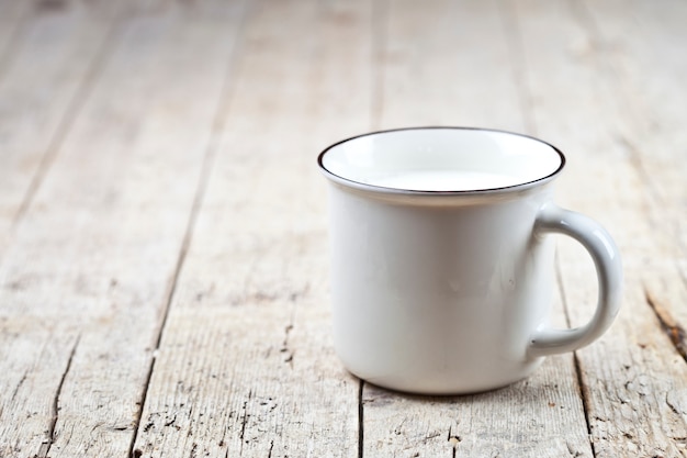 Frische Milch auf weißer keramischer Schale auf rustikalem Holztisch