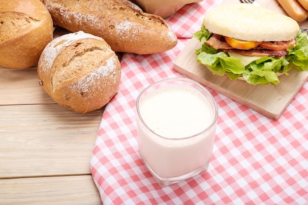 Foto frische milch mit frühstück auf einem hölzernen hintergrund