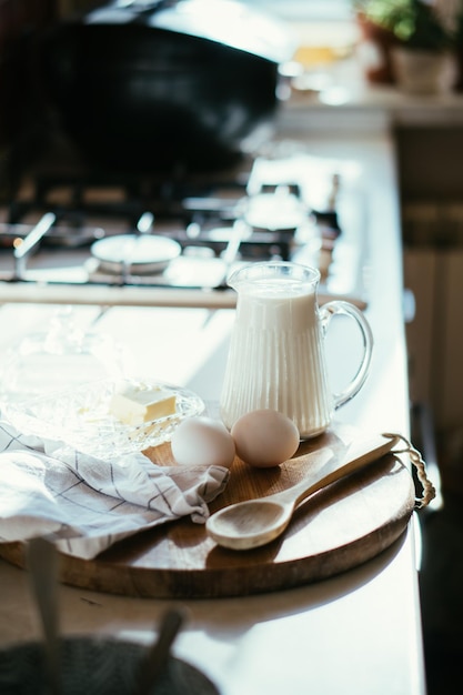 Frische Milch und Eier auf Holzbrett in echter Wohnküche mit natürlichem Licht