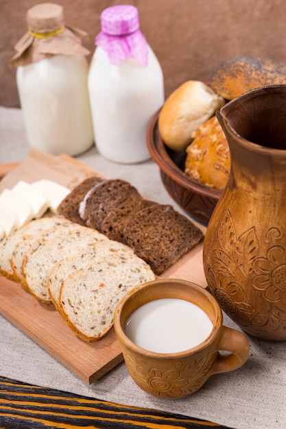 Frische Milch, Vollkornbrot und Käse werden auf einem hölzernen Schneidebrett für einen gesunden, rustikalen Snack serviert