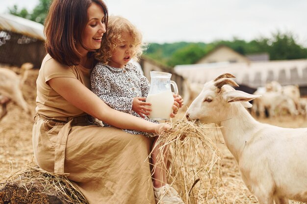 Frische Naturmilch Junge Mutter mit ihrer Tochter ist im Sommer mit Ziegen auf dem Bauernhof