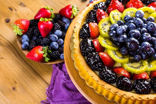 Frische Obsttorte auf Tortenständer auf Holztisch.