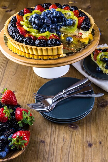 Frische Obsttorte auf Tortenständer auf Holztisch.