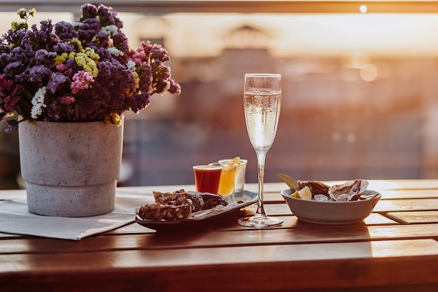 Frische offene Austern mit einem Glas gekühltem Prosecco-Wein und einer Reihe von alkoholischen Cocktails, die auf dem Tisch serviert werden. Delikatessen mit Meeresfrüchten