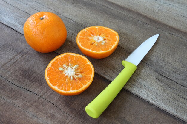 Frische orange Früchte auf Holzfußboden platziert und Messer Acryl.