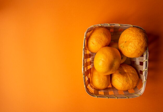 Frische orange Mandarinen in einem Korb auf einem orange Hintergrund