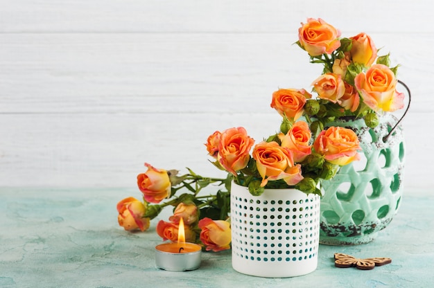 Frische orange Rosen blüht im tadellosen Vase und in brennender Kerze