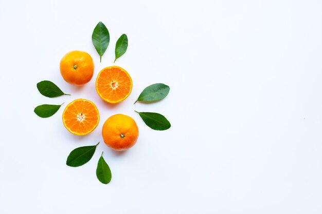 Frische orange Zitrusfrucht mit grünen Blättern auf Weiß.