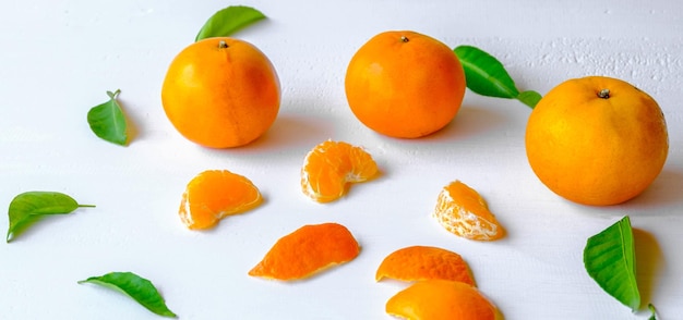 Frische Orangenfrucht und grünes Orangenblatt auf einer hölzernen Draufsicht des weißen Hintergrundes