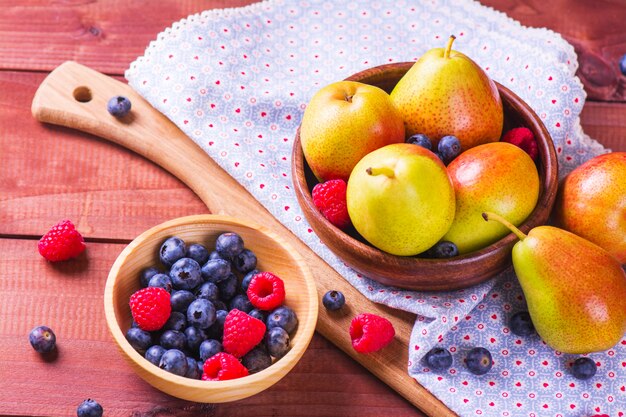 Frische organische Birnen und Beeren auf einem rustikalen Hintergrund