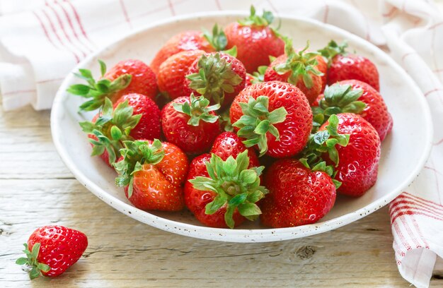 Frische organische Erdbeeren in einer weißen Platte auf einem Holztisch