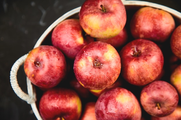 Frische organische rote Äpfel in einem Korb auf Schwarz