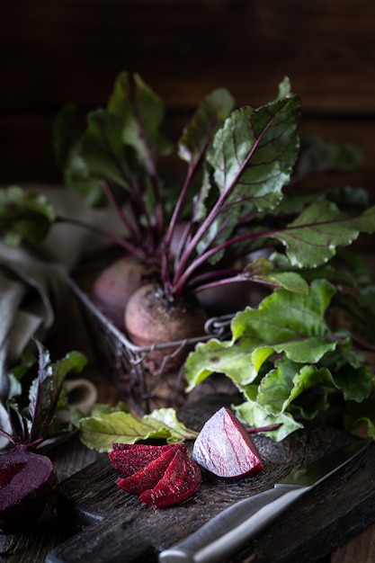 Frische organische rote Rüben mit Blättern in einem Weidenkorb auf einem Holztisch. Natürliches Bio-Gemüse. Herbsternte. Rustikal