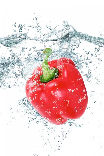 Frische Paprika fallen in Wasser