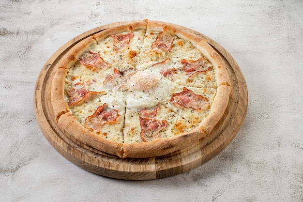 Frische Pizza Carbonara mit Schinken und Rührei auf dem konkreten Hintergrund