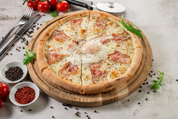 Frische Pizza Carbonara mit Schinken und Rührei auf dem konkreten Hintergrund