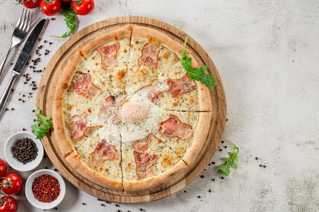 Frische Pizza Carbonara mit Schinken und Rührei auf dem konkreten Hintergrund