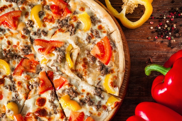 Frische Pizza mit Fleisch, Pfeffer, Tomaten und Käse-Nahaufnahme. Italienische Küche.