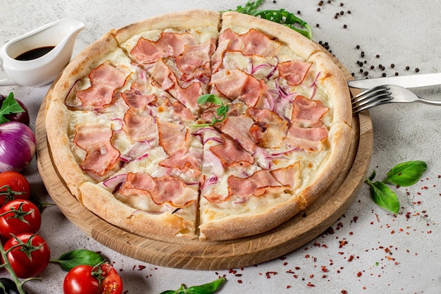 Frische Pizza mit Fleisch und Schinken auf dem konkreten Hintergrund