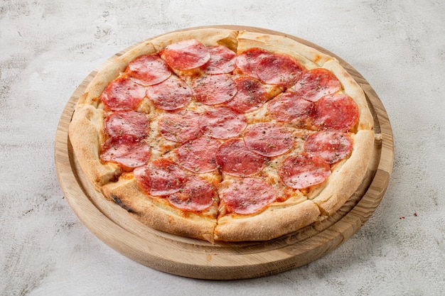 Frische Pizza mit Fleisch und Schinken auf dem konkreten Hintergrund