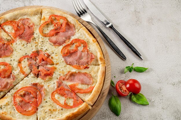 Frische Pizza mit Fleisch und Schinken auf dem konkreten Hintergrund