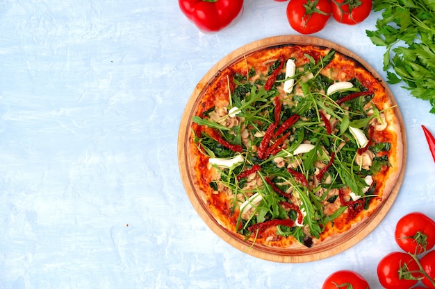 Frische Pizza mit Kräutern und sonnengetrockneten Tomaten auf grauer Tischoberansicht