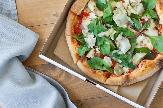 Frische Pizza mit Tomaten, Käse und Pilzen auf Holztisch Nahaufnahme.