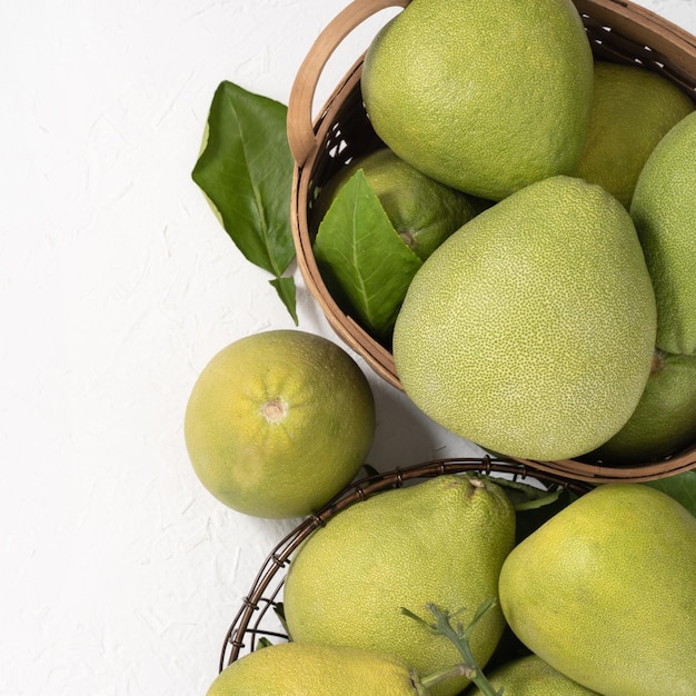 Frische Pomelo-Grapefruit im Bambuskorb mit grünem Blatt auf hellweißem Hintergrund Saisonobst für MidAutumn Festival Draufsicht Flache Lage