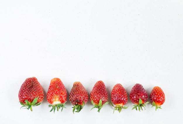 Frische reife Erdbeeren liegen in einer Reihe von groß bis klein. Kopieren Sie den Speicherplatz oben