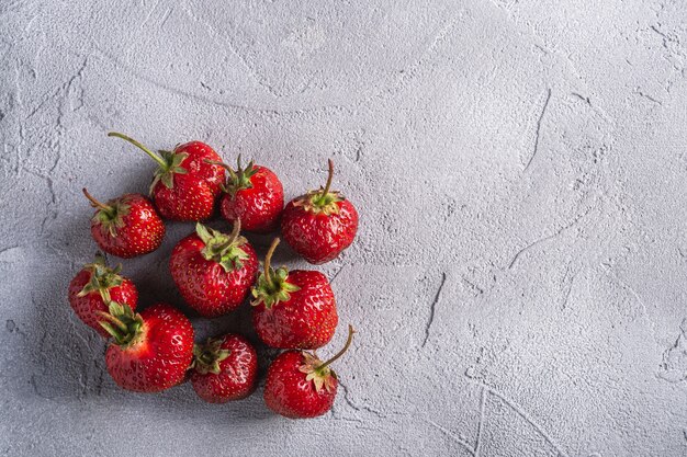 Frische reife Erdbeerfrüchte, Sommervitaminbeeren auf grauem Steinhintergrund, Kopierraum der Draufsicht