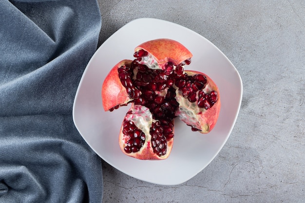 Foto frische reife granatäpfel mit samen auf weißen teller gelegt.