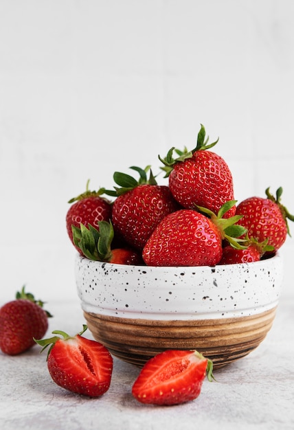 Frische reife köstliche Erdbeeren in einer weißen Schüssel auf einem grauen Steinhintergrund