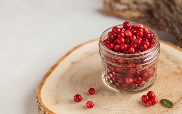 Frische reife Preiselbeeren in einem transparenten Glas auf einem Holzständer. Herbst, nützliche Beeren. Ernte..