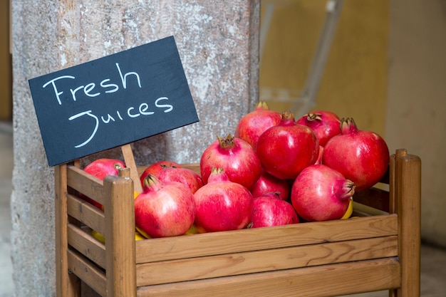 Frische reife rote Granatäpfel in Holzkiste mit frischen Säften der Aufschrift